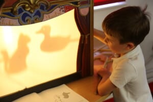 A child playing a with a shadow puppet theatre