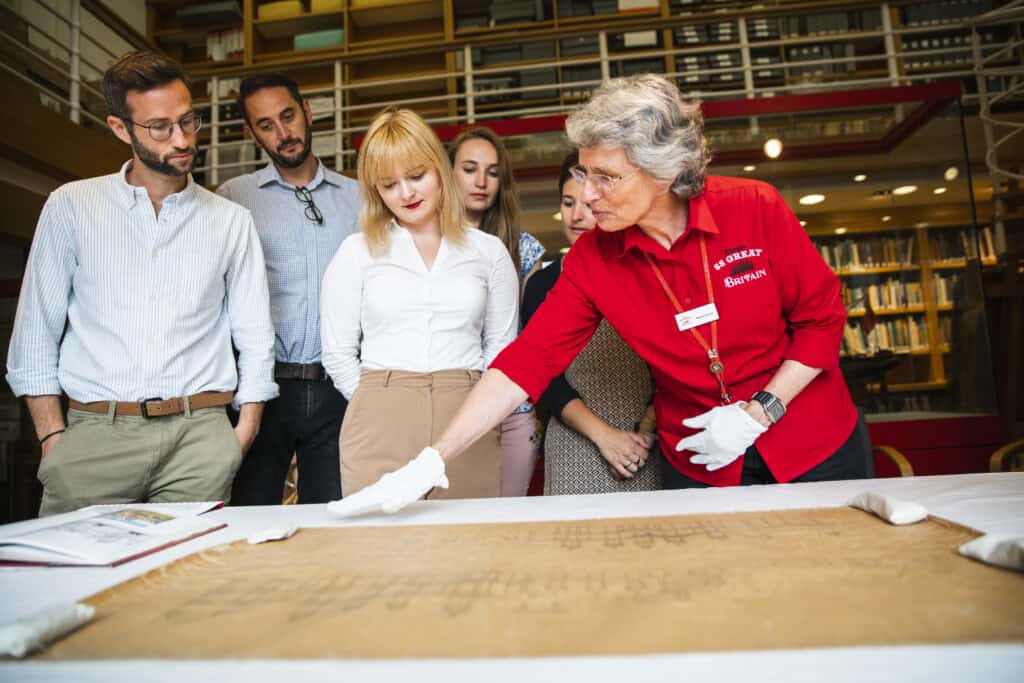 A volunteer in the library showing visitors a historical object