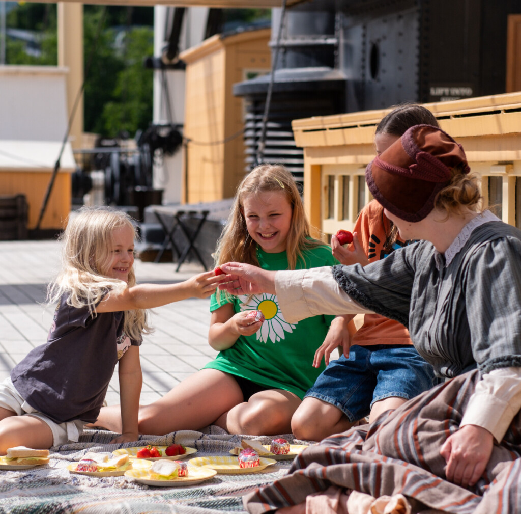 3 girls enjoying a picnic on the deck of the SS Great Britain with a Victorian lady